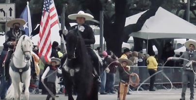 Rodeo parade Flag bearer on horseback with rope twirlers behind (Screenshot Houston rodeo 2022)